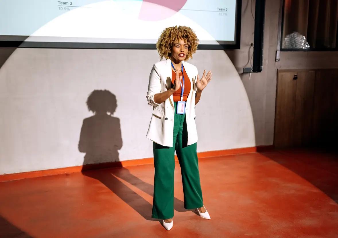 A woman on stage giving a persuasive speech at an event.